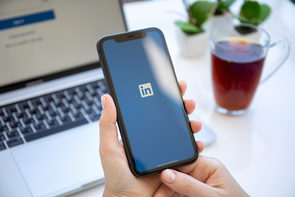 Woman working on cell phone on her personal brand in LinkedIn.