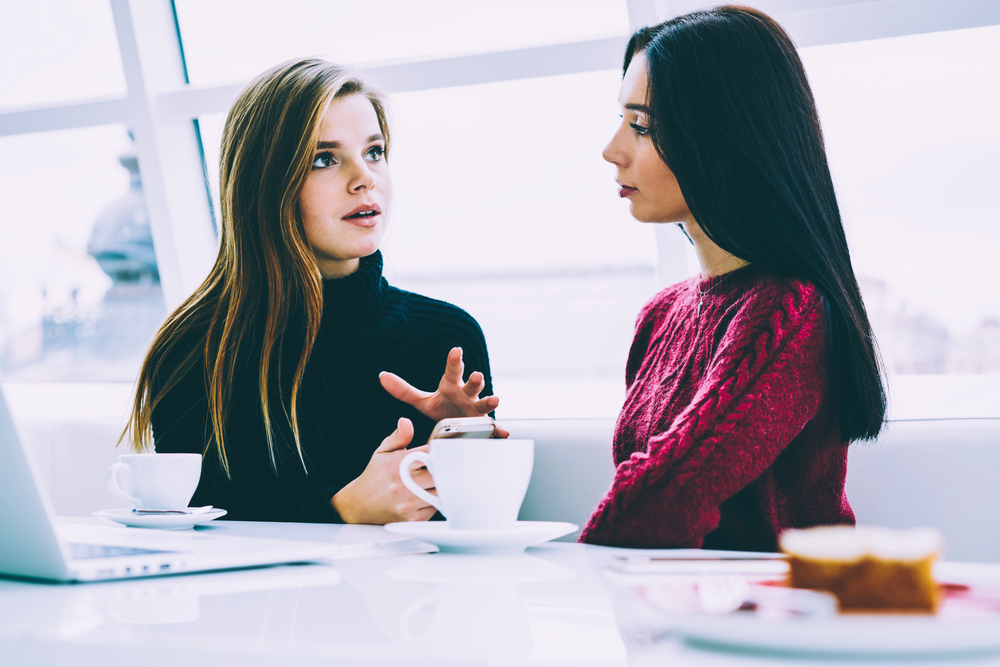 Two business women connecting to target client by writing clear messaging.