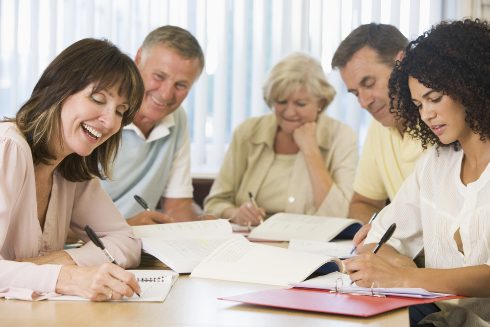 Group of people sitting at a table writing together.
